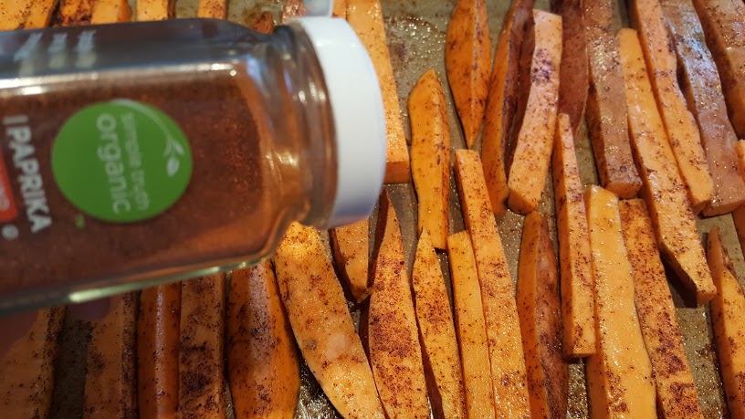 Seasoning the cut sweet potatoes for the Whole30 Loaded Sweet Potato Fries