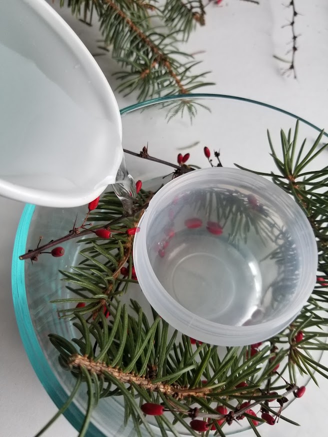 filling decorative ice bowl with branches and berries